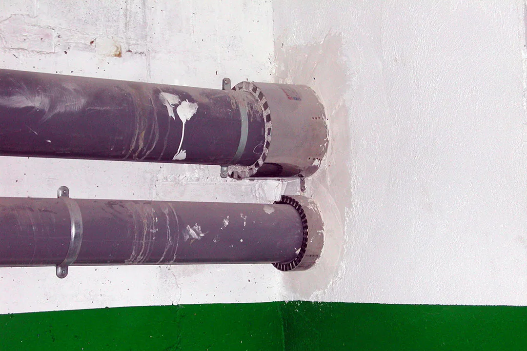 Collarines intumescentes instalados en el paso de dos tuberías de PVC a través de un muro, sellado cortafuegos
